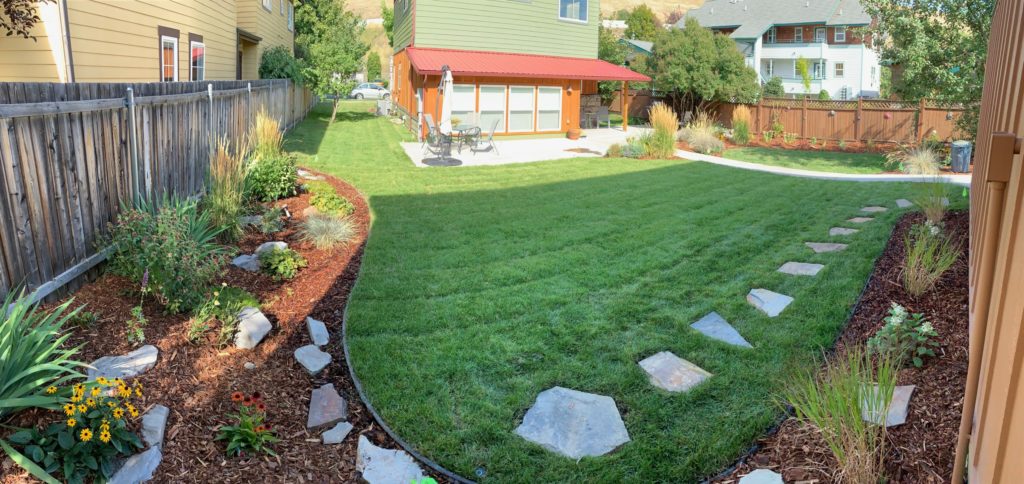 Custom stone walkway through green grass surrounded by landscape features.
